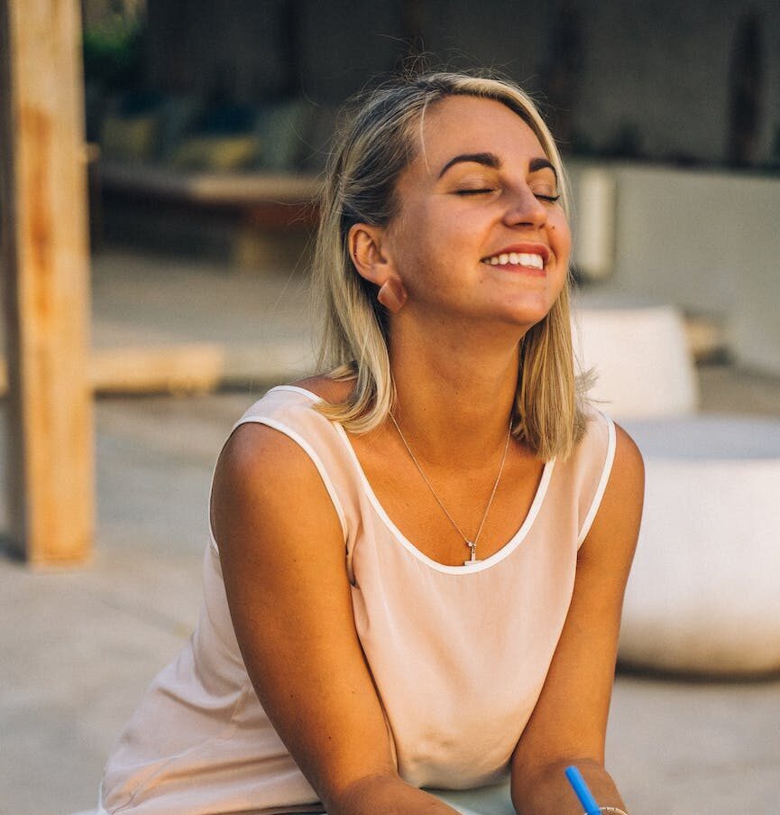 a smiling woman sitting | To be yourself in a world that is constantly trying to make you something else is the greatest accomplishment.