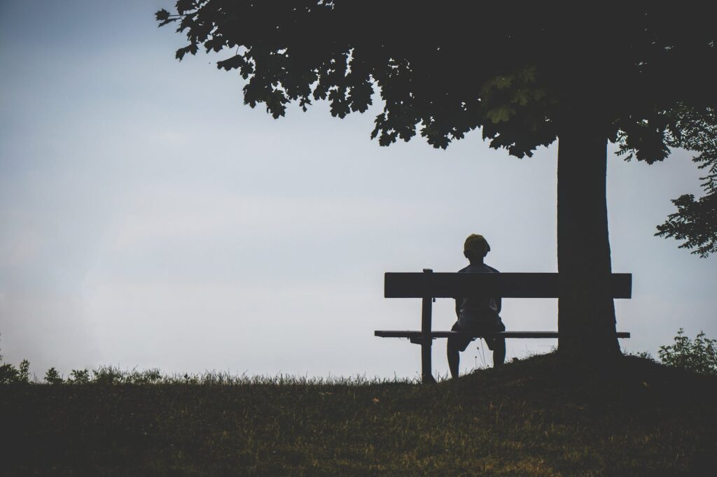 strange person sitting on bench under tree