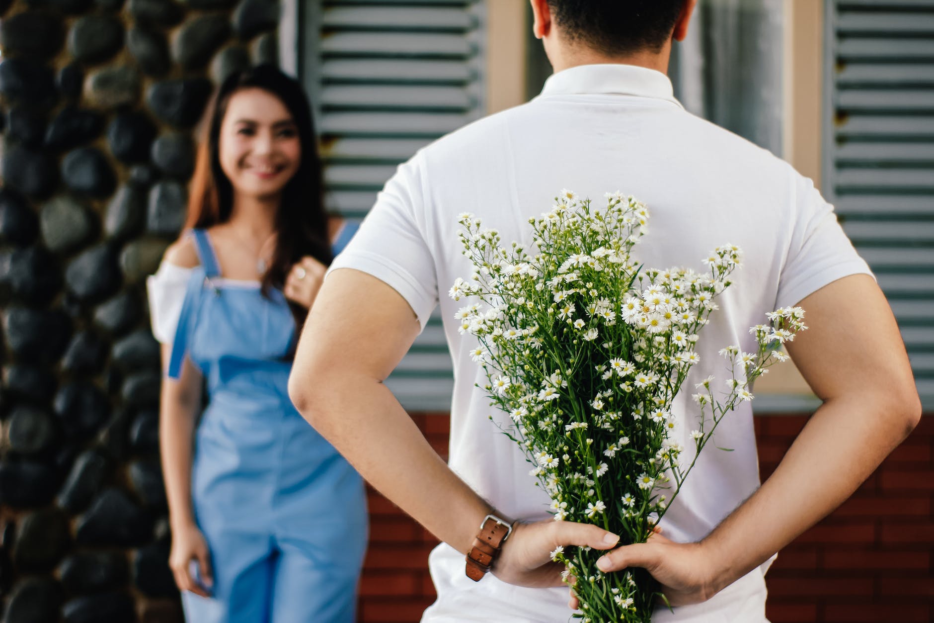 man holding baby s breath flower in front of woman standing near marble wall | Happy international day of happiness: 8 Tips on happiness