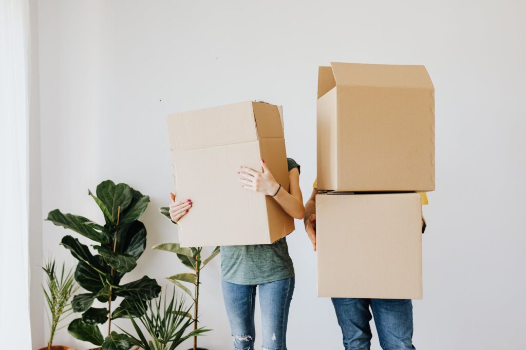Bridge Mortgage: Change Your House Before Selling Yours | couple carrying cardboard boxes in living room