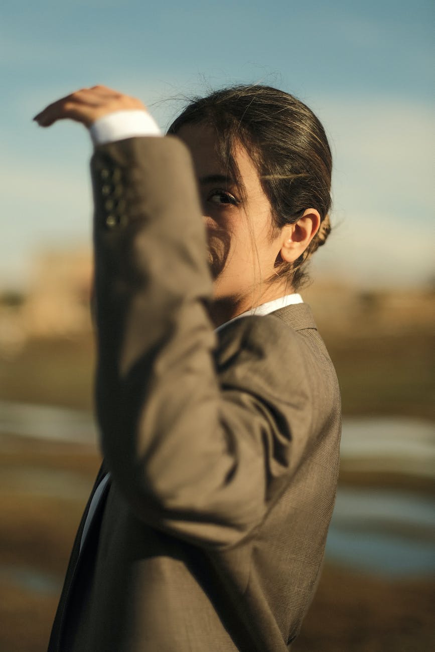 pexels-photo-15617831 - The Paris Post photo of a beautiful young girl in a jacket covering her face with her raised hand