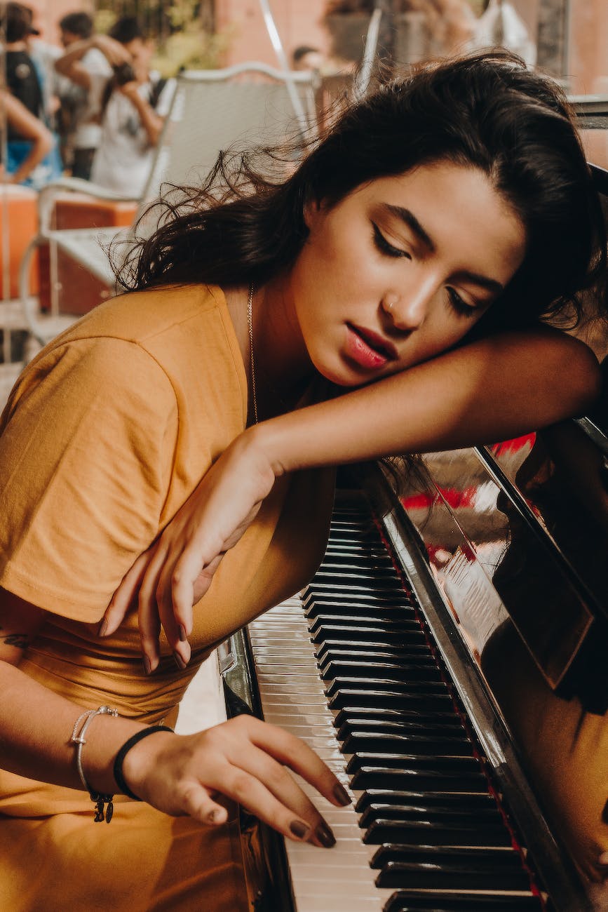 pexels-photo-1885213 - The Paris Post woman lying her head on piano | 9 Benefits of Listening to Music: Advancing Your Brain Power. There are several benefits of listening to music. I believe music is a fundamental part of our senses and activities. It also plays an important role in mood enhancement.