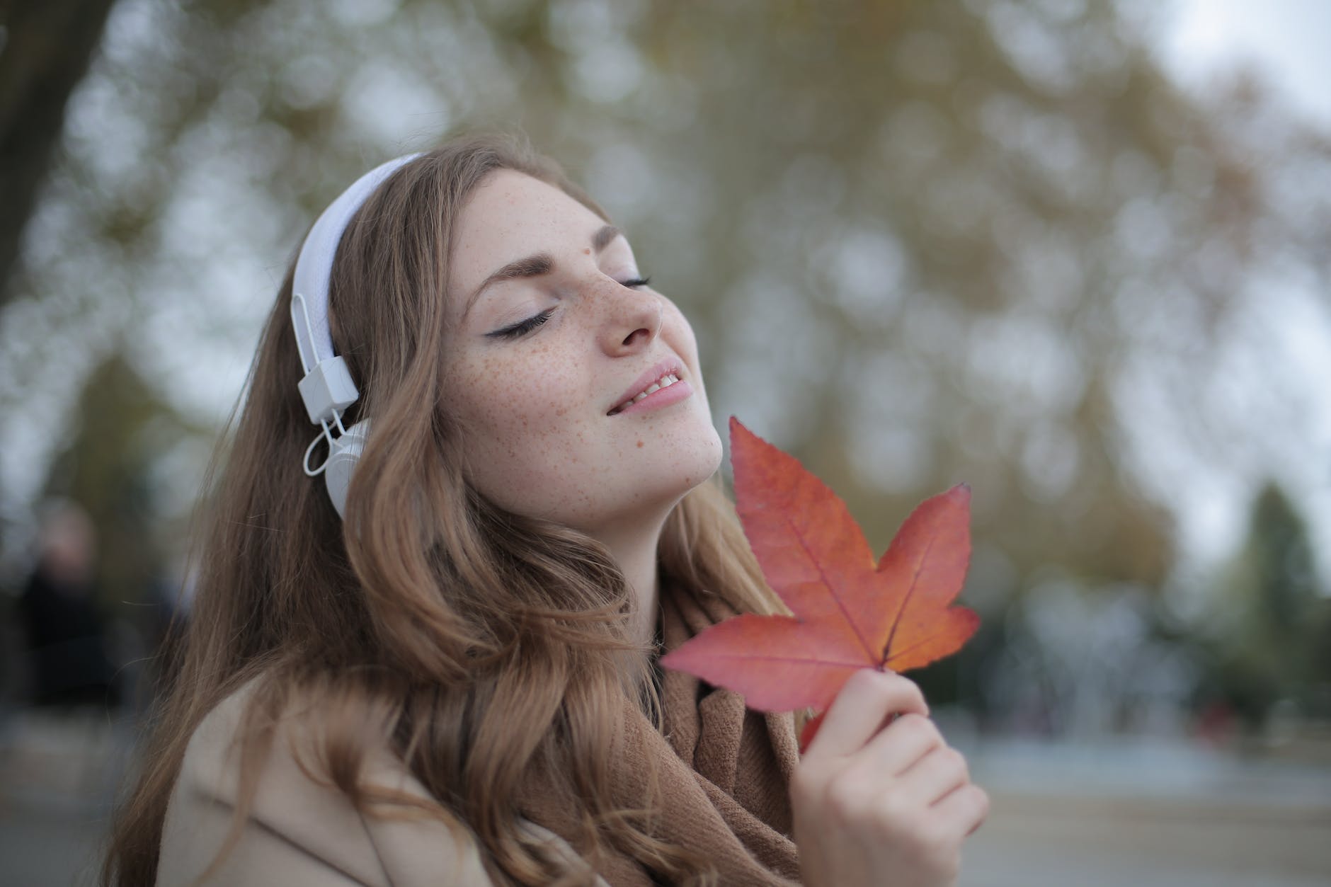 pexels-photo-3776557 - The Paris Post young satisfied woman in headphones with fresh red leaf listening to music with pleasure while lounging in autumn park
