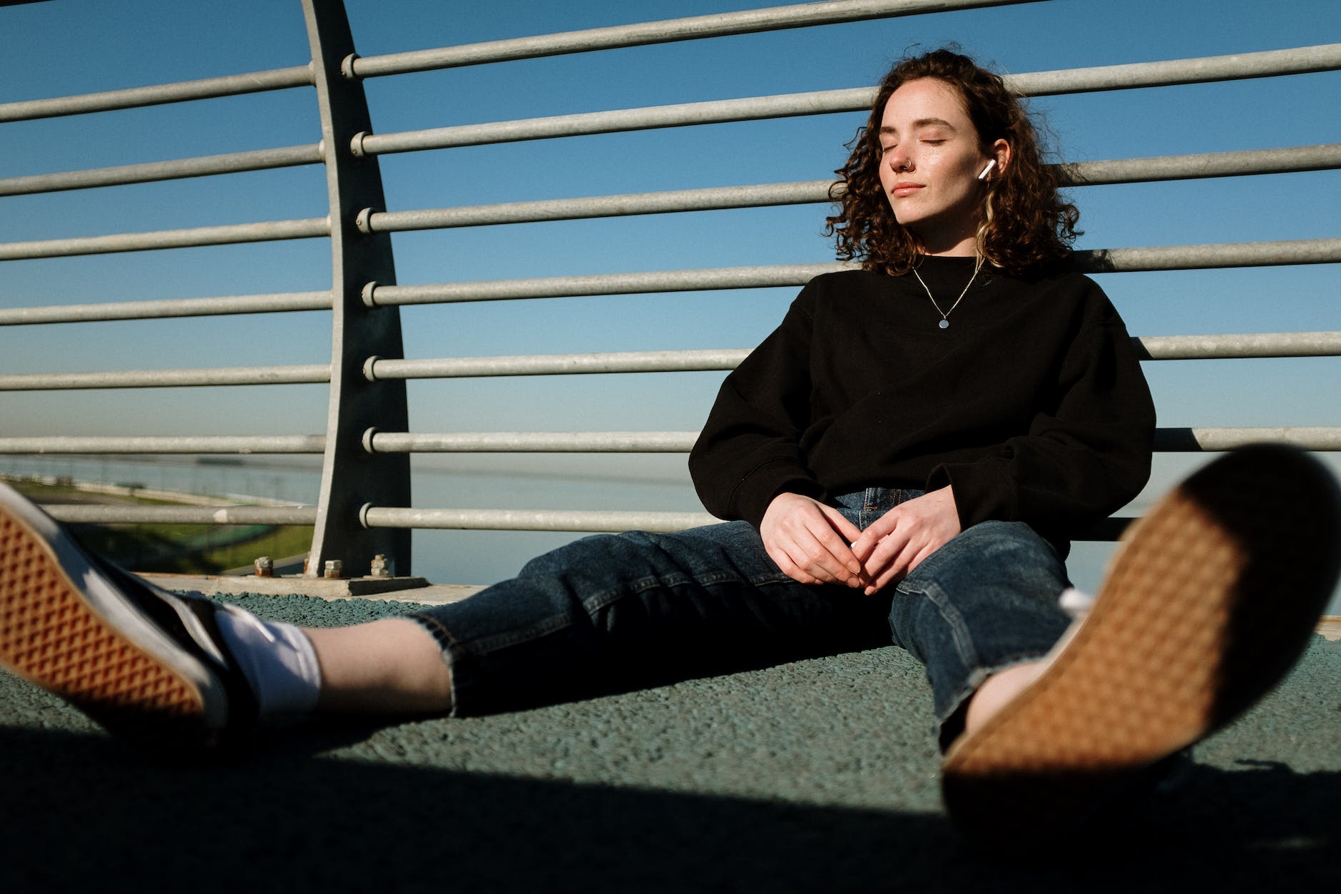 woman in black long sleeve shirt and blue denim jeans sitting on green grass field during. 9 Benefits of Listening to Music: Discover inner soul power